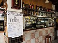 Interior de un típico bar de barrio de Montevideo, donde se aprecia un cartel invitando a inscribirse a un campeonato de truco.