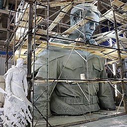 החלק העליון של פסל החייל, על רקע דגם טיח בגובה 2.5 מטר