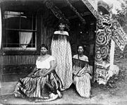 Tourist guides Sophia Hinerangi (standing), Kati and another, outside Hinemihi meeting house at Te Wairoa. Taken by Elizabeth Pulman about 1881
