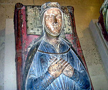 Фотография средневековой гробницы с изображением Изабеллы наверху. Она лежит, сцепив руки, в синем платье.