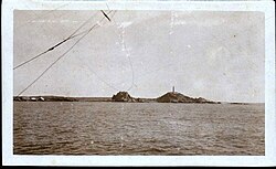 Fotografía del Faro y el pueblo Cabo Blanco tomada desde un buque.