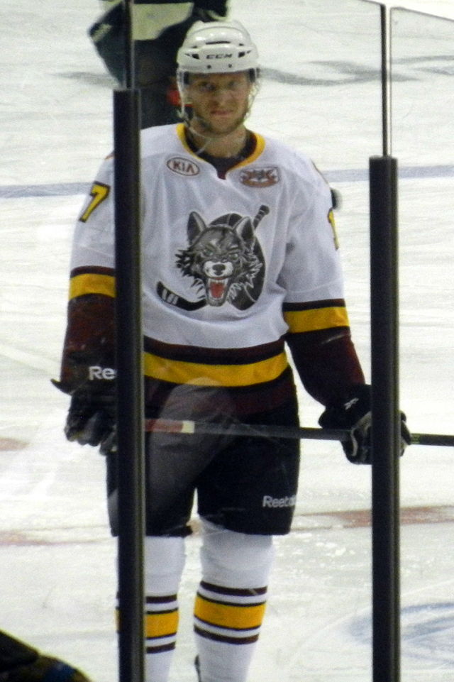 Photographie couleur d’un joueur de hockey en uniforme; portrait en pied
