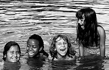 Photo en noir et blanc représentant quatre petites filles jouant dans l'eau.