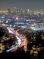 Photographie du centre-ville de Los Angeles vu depuis des collines éloignées, la nuit.
