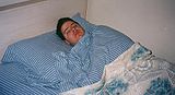 Man sleeping striped-sheets.JPG