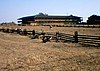 Photograph of the Petaluma Adobe, a broad, low, two-story building with wide verandas amidst open grasslands.