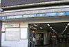 A brown-bricked building with a rectangular, light blue sign reading "STOCKWELL STATION" in white letters all under a light blue sky