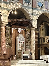 The seat of the Archbishop of Westminster in 2024. The coat of arms of the incumbent Cardinal Vincent Nichols is placed above. Westminster cathedral bishop seat.jpg