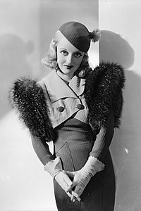 Bette Davis in the 1934 film Fashions of 1934, wearing stylish daywear designed by Orry-Kelly.