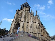 Vue d'une église ancienne située en haut d'un escalier et avec un clocher en ardoises