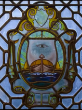 The school's traditional emblem depicted in a stained glass window in the main building LSTM Stained Glass Emblem.png