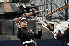 Two members of the United States Marine Corps Silent Drill Platoon get ready to catch their rifles which they have tossed up in the air.