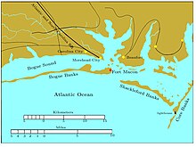 Bogue Banks is a long, narrow island extending from the left edge to past the middle of the chart. Fort Macon is at its eastern end. About two miles to the southeast is the western end of Shackleford Banks, which extends to the east southeast about seven miles. It is separated by a narrow inlet from Core Banks, which extends off the chart to the northeast. Behind these banks are the sounds, ranging in width from one to five miles. Carolina City, Morehead City, and Beaufort are sited on the sounds, all within 10 miles of Fort Macon. The Atlantic and North Carolina Railroad begins in Morehead City and runs off the map to the northwest.