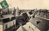 Vue d'un bourg prise d'un point haut, rue et maisons en contrebas, église en arrière plan.