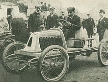 Photo d'un homme en tenue de ville au volant d'une voiture monoplace.