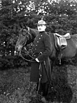 Ridande polis från Göteborg iklädd uniform, vid sin sadlade häst. (1909).