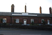 A single story red-brick row with above the main door a raised parapet including a dedication plaque.