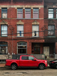 A photo of a red brick rowhouse with three stories.