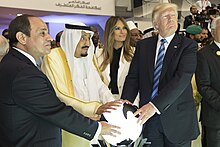 Trump, King Salman of Saudi Arabia, and Abdel Fattah el-Sisi place their hands on a glowing white orb light at waist level