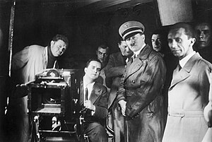 Adolf Hitler, Joseph Goebbels, and others watch filming at Ufa, 1935. Bundesarchiv Bild 183-1990-1002-500, Besuch von Hitler und Goebbels bei der UFA retouched.jpg