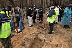 ロシア軍撤退後のイジュームにおいて発見された集団墓地の現場検証を行う警察官。