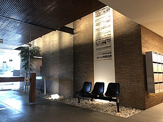 Photographie du chimigramme de Pierre Cordier, oeuvre d'art avec tâches noires sur fond blanc. En premier plan, fauteuils plastique, dalle béton, porte vitrée