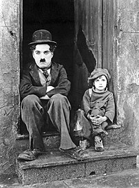 Photographie d'une scène du film muet américain Le Kid avec Charlie Chaplin et Jackie Coogan. Le film, en format noir et blanc et 35 mm, sort en avant-première à New York, le 21 janvier 1921. (définition réelle 1 226 × 1 496)