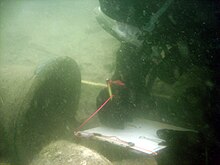 A maritime archaeologist with the Lighthouse Archaeological Maritime Program in St. Augustine, Florida, recording the ship's bell discovered on the 18th century "Storm Wreck." Diver&shipsbell.jpg