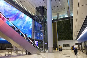 旅客捷運系統中場客運廊車站，外牆設垂直綠化及Graham Jones創作，寬8米、長達40米的巨幅藍色鑄造玻璃藝術牆