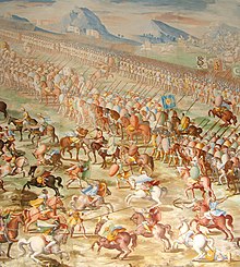 A painting of a battle with a long line of mounted riders side by side in front of a line of marching men. In front of the riders are a number of individual horsemen fighting.