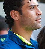 Suntanned man in suit holding a golden statue (World Cup trophy) in his hand while smiling happily