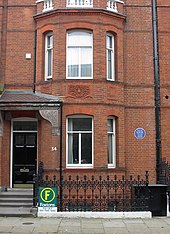 A semi-detached red-brick Georgian house, with a small blue plaque on the wall.