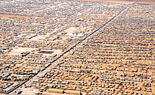 An aerial view of a portion of the Zaatari refugee camp which contains a population of 80,000 Syrian refugees, the largest Syrian refugee camp in the world. An Aerial View of the Za'atri Refugee Camp.jpg