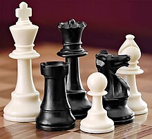 A selection of white and black chess pieces on a checkered surface.