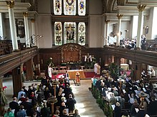 Christian worshippers attend an Easter Sunday church service at St James's Church in London; the cross in the chancel is draped with a white shroud, symbolizing the resurrection Easter Sunday 2016.jpg