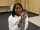Девушка демонстрирует шарф в процессе вязания на пальцах