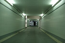 Tunnel piéton éclairé par des néons en haut des murs.