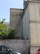 Photographie en couleurs d'une tour rectangulaire plaquée contre le pignon d'un autre bâtiment.