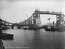A black and white photograph of the Tower Bridge during its construction.