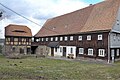 Wohnstallhaus (Umgebinde) und Seitengebäude eines Bauernhofes, vor dem Haus Granitwassertrog