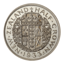 A coin featuring the Coat of Arms of New Zealand, surrounded by Maori wood carvings and the encircling text "NEW ZEALAND HALF CROWN 1933."