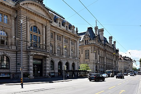 Le sud de la place vue de l'est en 2020 : au premier plan, le siège de la Banque Cantonale Vaudoise, puis l'Hôtel des Postes et, au fond, le bâtiment de la banque UBS.