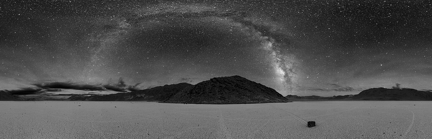死亡谷跑道湖的360°夜景。中间可见的弧线是银河系。地面上可以看到一块迷踪石和其他石头。