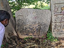 Local pepole curiesly watching the Gulakamale 14th-century Kempanna Hero-stone (Kannada)