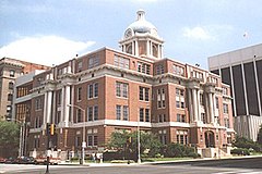 A four-story red brick and light stone building in a city environment on a sunny day.