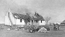 Boer civilians watching British soldiers blow up their house with dynamite after they had been given 10 minutes to gather their belongings. VerskroeideAarde1 crop.jpg