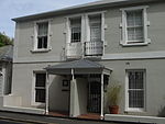 Semi-detached double storey dwelling probably Victorianised. Full hipped corrugated iron roof; plaster quoining around upper floor openings; and a plaster band at position of removed verandah; sash windows of later Victorian type. Type of site: House Current use: House.