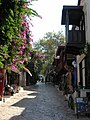 Une rue à Kaş avec des maisons traditionnelles et une tombe lycienne en arrière-plan