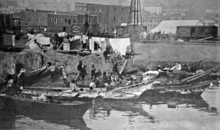 Native American canoes along the bank of a sandy island, with a camp onshore