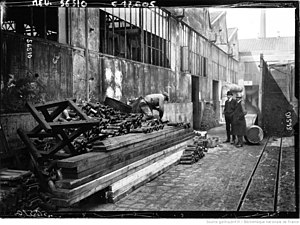 Photographie en noir et blanc d'obus le long d'une usine.